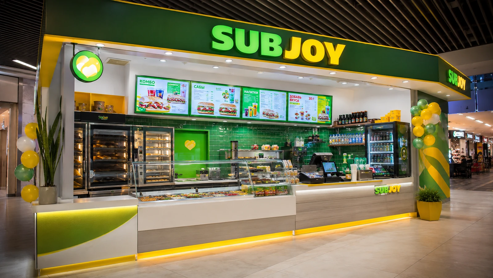 Ресторан быстрого питания Subjoy в торговом центре со светящейся зелено-желтой вывеской и витриной с ингредиентами.